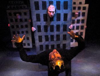 Greg Marzullo (wearing crown) is overwhelmed by the crush of buildings (represented by Philip Fletcher and the rest of the ensemble)